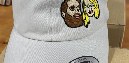 Gray baseball hat custom embroidered with a man and a woman’s face.